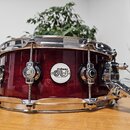 Vínový snare drum s chromovaným obručováním a mechanismem napínání. Uprostřed korpusu je bílý oválný štítek s nápisem drumz DW DESIGN SERIES. Povrch…