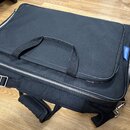Černá textilní přepravní taška s rukojetí a ramenním popruhem. Na pravém boku je přišitý modrý štítek s bílým nápisem pedaltrain. Povrch materiálu je…