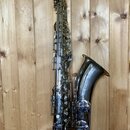 Stříbrný saxofon s kovovým povrchem a dřevěným mouthpiecem. Na zvonu je vyryto logo s nápisem "The King". Nástroj vykazuje známky používání v podobě…