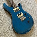 Modrá elektrická kytara s výraznou plamenovou strukturou dřeva na topu. Na těle jsou dva humbuckery s krémovými rámečky, tři ovládací knofíky a přepí…