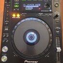 Černý digitální DJ player značky Pioneer, model CDJ-850 MULTI PLAYER. Zařízení má velký kruhový jog wheel, fader tempo a řadu ovládacích tlačítek s n…