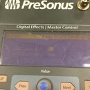 Detailní záběr na ovládací panel zařízení značky PreSonus s nápisem Digital Effects | Master Control. Uprostřed je umístěn LCD displej, na kterém je…