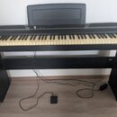 Černý digitální piano s klaviaturou a integrovaným stojanem. Na horní části je nápis KORG a nad klávesami je umístěna černá hudební stránkovka. Nástr…