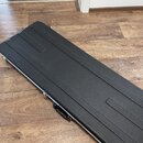 Černý obdélníkový tvrdý kufřík s texturovaným povrchem a kovovými hranami. Kufřík má v horní části dvě prohlubně a na boku černou plastovou rukojeť s…