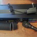 Na fotografii je černý rackový procesor s nápisem TC HELICON a označením VOICELIVE RACK. K zařízení patří černý dynamický mikrofon s logem TC HELICON…