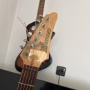 Detail hlavy elektrické kytary z přírodního dřeva s nápisem Ibanez. Na hlavě jsou umístěny šest chromovaných ladících kolíčků. Povrch dřeva vykazuje…