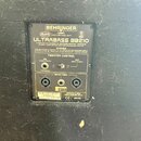 Záběr na zadní panel basového komba značky BEHRINGER, model ULTRABASS BB210. Panel obsahuje nápisy RoHS, www.behringer.com a varovný text o hladině h…