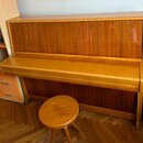 Vertikální piano v dřevěném provedení s výraznou svislou strukturou sletu. Nástroj má uzavřenou klávesnici a je vybaven doprovodnou dřevěnou stoličko…
