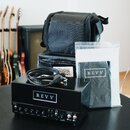Černý kytarový zesilovač s nápisem REVV na předním panelu a označeními D20, INPUT, GAIN, TREBLE, MIDDLE, BASS, VOLUME. Za přístrojem je černý textiln…