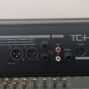 Černý rackový procesor s nápisem TC HELICON VOICELIVE RACK. Přední panel obsahuje různé vstupy a výstupy s popisky jako MIC, INPUTS, OUTPUTS, DIGITAL…