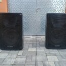 Dva černé reproduktorové boxy s kovovými mřížkami přes celé přední strany. V dolní části obou boxů je bílý nápis Voice Master. Povrch krytů vykazuje…