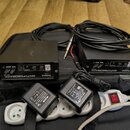 Na černé podložce leží dvě identické černé krabičky s nápisy Roland ANTI-FEEDBACK AF-70. Každé zařízení má na předním panelu ovládací prvky LOCK, CLE…