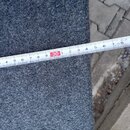 Fotografie zachycuje detail šedého plstěného materiálu s hrubou texturou. Přes povrch je položen bílý natahovací metr, který ukazuje rozměr od 20 do…