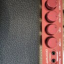 Detailní pohled na červený ovládací panel s nápisem promethean. Panel obsahuje pět otočných knoflíků s popisky Master, High, High Mid, Low Mid a Low,…