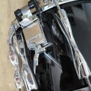 Detailní pohled na černý buben s chromovaným kováním. Na kovovém mechanismu je vyryt logo a nápis YAMAHA. Povrch nástroje je glossy, s viditelnými od…