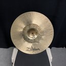 Zlatavý kovový činel s viditelným opracováním povrchu ve formě jemných koncentrických rýh. V dolní části je černým písmem uveden nápis Zildjian. Povr…