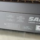 Detailní pohled na zadní část šedého zařízení s nápisem SAMSON a označením L2000 LIVE MIXING CONSOLE. Na štitku je uvedeno sériové číslo L2000 230V L…