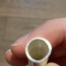 Detailní pohled na horní otvor kovového, stříbrného nástroje nebo příslušenství. Předmět je držen v ruce a má kruhový tvar s hladkým povrchem. Žádné…