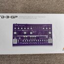 Bílá krabice s nápisem TD-3-GP a popisem Analog Bass Line Synthesizer with VCO, VCF, 16-Step Sequencer, Distortion Effects and 16-Voice Poly Chain. N…