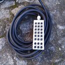 Černý kabel s bílým obdélníkovým rozbočovacím modulem. Modul obsahuje 20 ženských XLR konektorů, které jsou v řadách očíslovány číslicemi 1 až 20. Po…