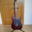 Elektrická kytara s tmavě červeným gradientem těla a černým hmatníkem. Na hlavě je bílý nápis sqr. Kytara má černý pickguard, dva humbuckery a je umí…