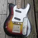 Elektrická kytara s polodupatým korpusem v barevném přechodu od černé přes červenou k žluté. Nástroj má bílý pickguard, dva snímače s černými kryty,…