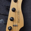 Hlava basové kytary z přírodního světlého dřeva s černými ladicími kolíky. Na povrchu je svisle napsán model Marcus Miller V5 a v horní části je logo…