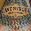 Detailní pohled na dřevěný nástroj s napnutými strunami. Na povrchu je vidět dekorativní nápis ANT. PETROF a pod ním text CZECHOSLOVAKIA. Ve spodní č…