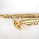 Zlatý saxofon s kovovým povrchem a dekorativním rytím na čase. Nástroj vykazuje známky používání v podobě drobných škrábanců a zaprášení. Na těle nás…