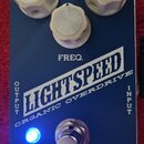 Modrý efekt pedál s nápisy LIGHTSPEED a ORGANIC OVERDRIVE. Na horní části jsou tři bílé plastové oválkové knoflíky, jeden z nich je označen jako FREQ…