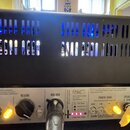 Detail zadního panelu černého kytarového zesilovače s ventilační mřížkou, přes kterou je vidět modré podsvícení. Na panelu jsou nápisy REVERB, RED BO…