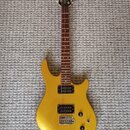 Zlatá elektrická kytara s tmavým hnedým hmatníkem a černou hlavou. Má dva humbuckery, jeden ovládací knoflík hlasitosti a jeden tónu. Na hlavě je vid…