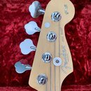 Hlava basové kytary z jasného dřeva s chromovanými ladičkami. Na povrchu je nápis Fender® JAZZ BASS® a text MADE IN U.S.A. V horní části je kulatý št…