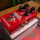 Červený efekt pedál s nápisy tc electronic, HALL OF FAME 2 a TRUE BYPASS. Na horní straně jsou čtyři černé oválné ovládací knoflíky a jeden stříbrný…