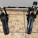 Černý dvojpedál na basový buben s kovovou spojovací hřídelí. Na obou pedálech je umístěno logo MAPEX v žluté barvě. Hřídel nese malý bílý štítek s ná…