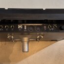 Záběr na zadní panel černého elektronického hudebního zařízení. Jsou zde vidět různé konektory s popisky: INPUT 9V=2A, TRIG 3/4, TRIG 1/2, FS2, FS1,…