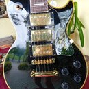 Černá elektrická kytara s gold hardwarem a zlatým lemováním. Na těle jsou dva humbuckery, Tune-o-matic kobyla a stopbar strunovník v zlatém provedení…