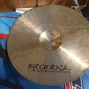 Kovový činel zlatavé barvy s viditelným kovánívým povrchem. Na povrchu je černý nápis „istanbul Agop Handmade cymbals from Turkey“. V centrální části…
