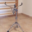 Chromovaný kovový stojan s černými gumovými koncovkami na nohách a horních držácích. Na středním sloupku je svisle napsán nápis "The Music Stand". Po…