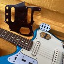 Modře třpytivá elektrická kytara s bílým pickguardem a dvěma snímači s jednoduchou cívkou. Vedle kytary leží náhradní tmavě červený pickguard s vzore…