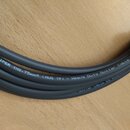 Šedý kabel s nápisem „The WIPER 1X0,75mm² (AWG 19) - Heavy Duty Guitar Cable by D“. Kabel je svázán zeleným suchým stahovadlem. Povrch izolace vypadá…