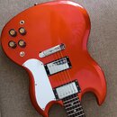 Oranžová elektrická kytara s dumpingovým tvarem korpusu a bílým pickguardem. Nástroj má dva humbuckery s chromovanými kryty a čtyři ovládací knofíky.…