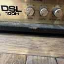 Detailní pohled na horní ovládací panel kytarového zesilovače zlaté barvy s nápisy DSL 100H, ON STANDBY a popisky potenciometrů ULTRA, CLASSIC, RESON…
