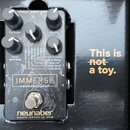 Černý efekt pedál s nápisem IMMERSE reverberator a značkou neunaber AUDIO EFFECTS USA. Zařízení má čtyři černé ovládací knoflíky s popisky fx level,…