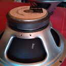 Fotografie zachycuje reproduktor z pohledu zespodu. Na horní části je vidět štít s nápisy CELESTION a G12T-75. Stříbrný kovový rám má v dolní části v…