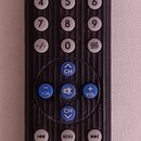 Černý plastový dálkový ovladač s řadou šedých a modrých tlačítek. V dolní části je bílý nápis CHUNGCHOP L307 LEARN REMOTE. Povrch ovladače vykazuje z…