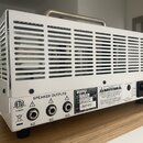 Zadní strana bílého kytarového zesilovače s kovovým šasi a horní rukojetí. Na spodním panelu je nápis SPEAKER OUTPUTS u tří výstupů s označením 8Ω, 8…