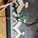 Detailní pohled na elektrické vodiče v různých barvách (červená, hnědá a černá). Část kabeláže je spojená pomocí černých stahovacích pásek a jeden ko…