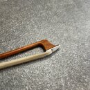 Detail smyčce s hnutým dřevěným دستهkem hnědé barvy. Spodní část smyčce je vyrobena ze světlého materiálu s viditelnou strukturou vláken. Na fotograf…