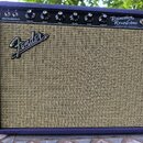 Kytarový kombozesilovač s fialovým potahem a béžovou textilní mřížkou. Na horním ovládacím panelu jsou nápisy Princeton Reverb Amp, Fender Musical In…